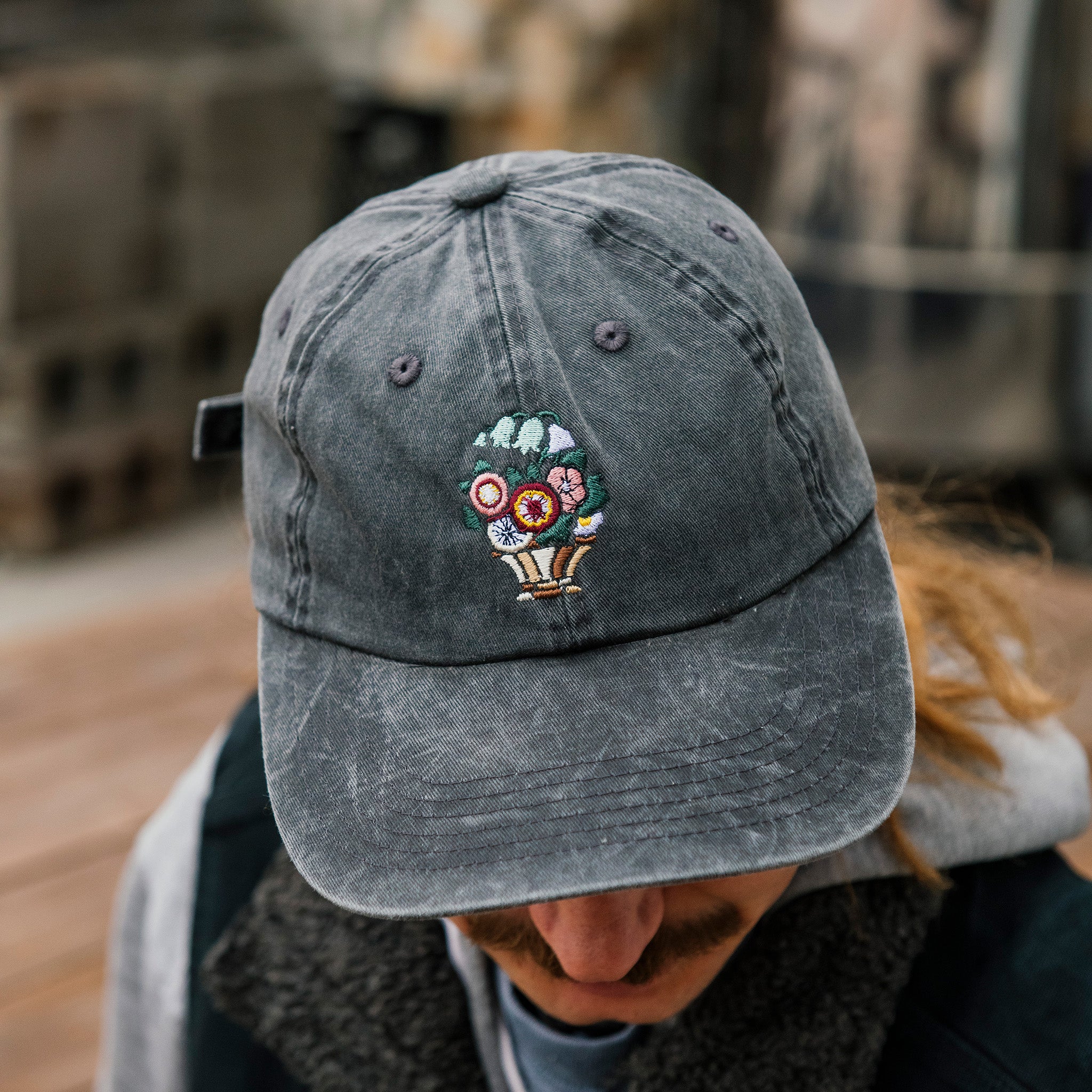 The dark gray Floral Hat features an embroidered bouquet of flowers in a brown and white vase.