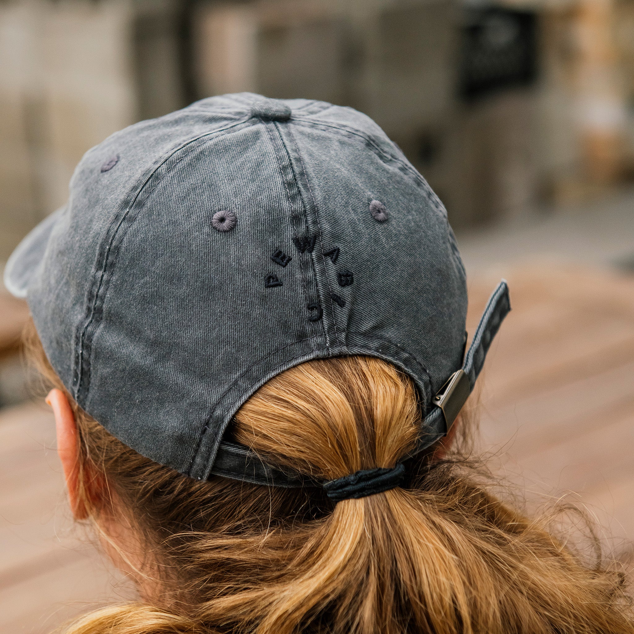 The back of the dark grap baseball cap features the embroidered Pewabic logo and an adjustable fabric strap. 