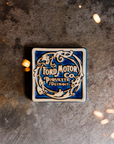 The Ford Piquette Tile has a vintage Ford design. The words "Ford Motor Co. Piquette Detroit" are written in decorative script. The words are surrounded by a swirly circular design.