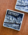 This two-tone Detroit Skyline tile is featured in the Viridian/Scrape color palette. The sky and water are in a shiny black glaze while the skyline, boat, and word are a creamy white color.