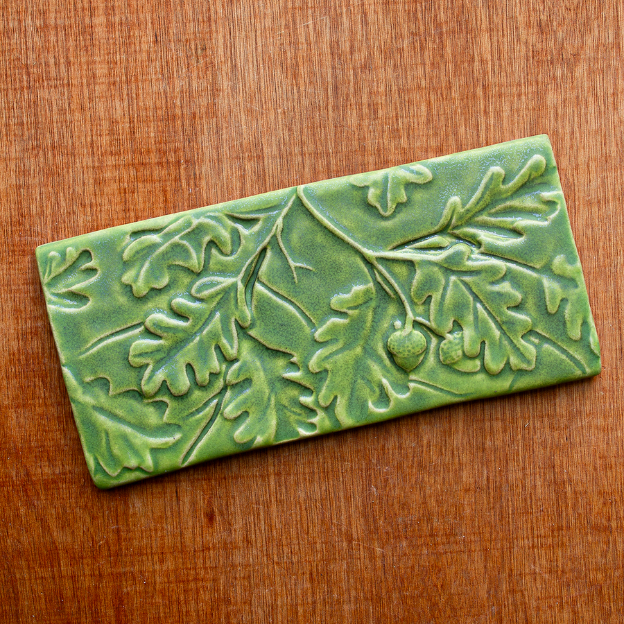 The Oak Leaves tile features high relief oak leaves and acorns hanging from a thin branch. The leaves are layered and giving the illusion of depth- like the many layers of leaves found on a flourishing tree. This tile features the matte bright light green Lime glaze.
