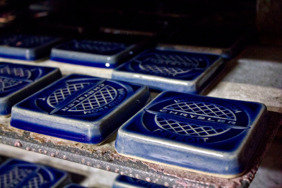 Glossy deep blue commemorative tiles come out of the kiln. Each tile features the Chrysler logo.