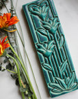 The Floral Tile features the matte turquoise Pewabic Blue glaze.