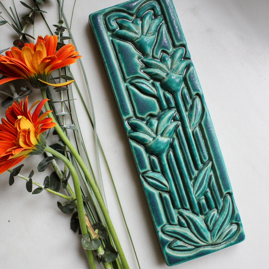 The Floral Tile features the matte turquoise Pewabic Blue glaze.