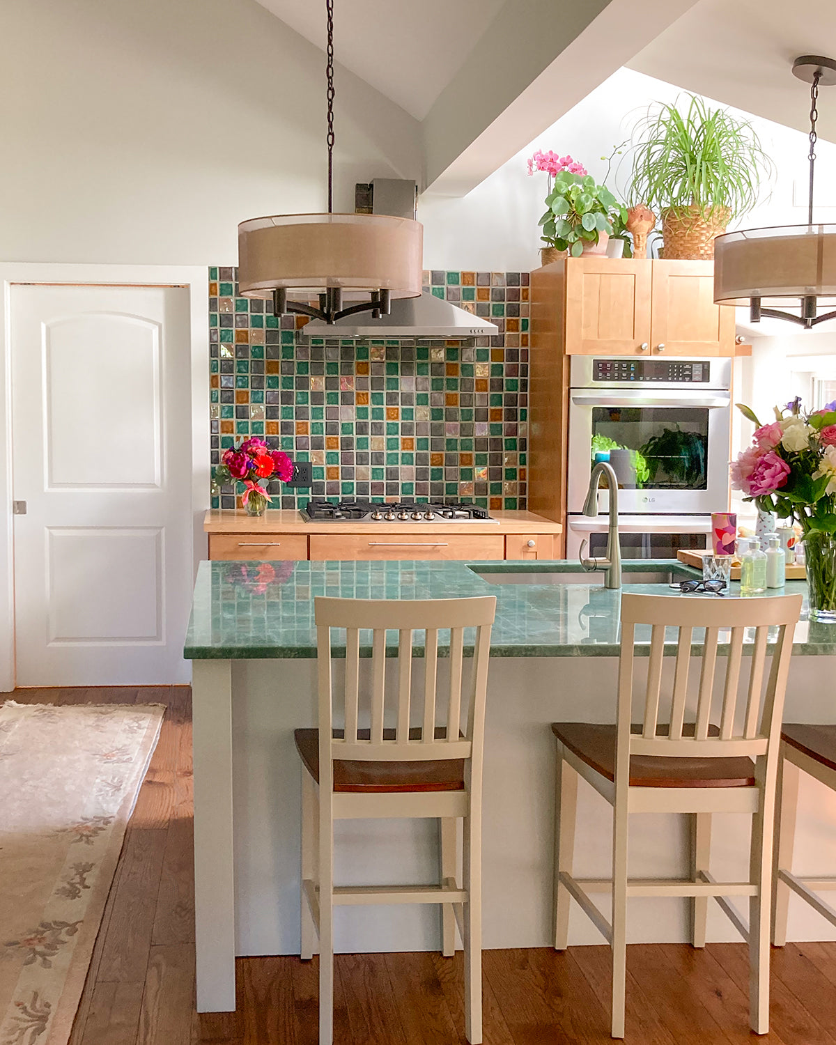 Multicolored tile backsplash in a kitchen with modern cabinets and a jade green countertop