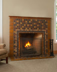 Lit fireplace in the center of two beige couches. The tile is rustic and comprised of a blend of brown and earth-tone tiles. A tasteful Iridescent custom-cut trim lines the border alongside brown tiles in an acorn motif.