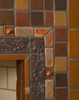 This fireplace tile is rustic and comprised of a blend of brown and earth-tone tiles. A tasteful Iridescent custom-cut trim lines the border alongside brown tiles in an acorn motif.