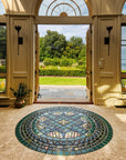 A custom, circular, tile medallion is the focal point of this photo which includes large doors opening to an impressive garden view. The tile design has elements of a compass and is rich in glossy blue and green glazes paired with a stark Aurora Iridescent glaze.