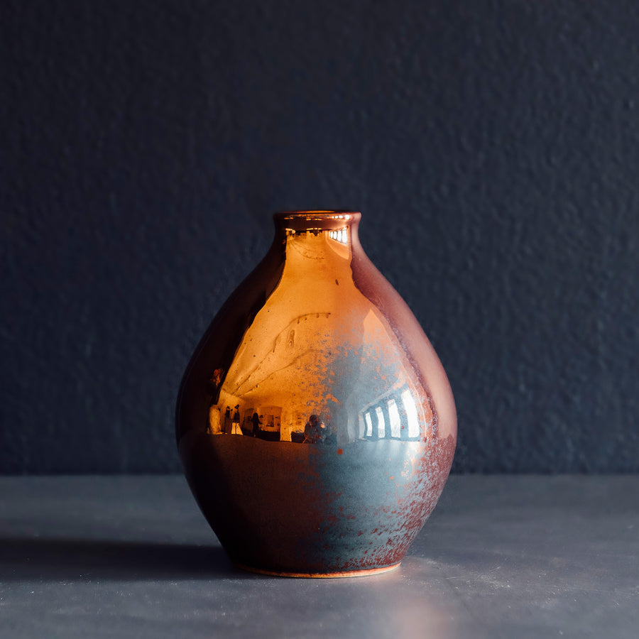 This Teardrop vase has a large blue-gray spot of flashing on it shiny copper surface.