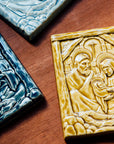 The Nativity Tile features the haloed holy family - Joseph, Mary and Baby Jesus - embracing under the wooden beams of the stable. Behind them, a window in the stone wall gives a glimpse of the Bethlehem star.