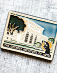 The bright white building of the Detroit Institute of Arts is featured in this hand painted tile. Large bushy trees frame the facade with the dark outline of the Thinker statue in front of it. Under the building design are the words "The Detroit Institute of Arts".