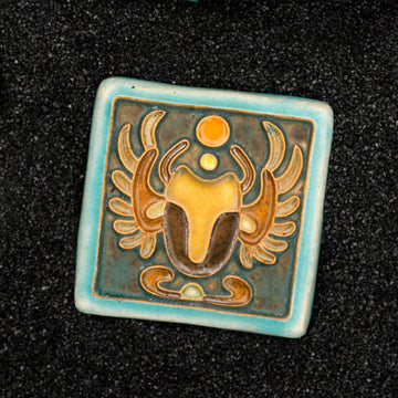 The Scarab Tile features a line drawing of a scarab beetle with wings outstretched and two small circles floating between its front arms. The design has classic Egyptian markings.