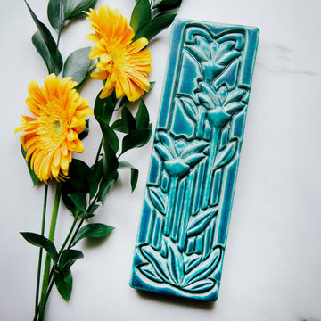 This large Floral Tile features three tall art deco-esque flowers on long straight stems with pointed leaves.