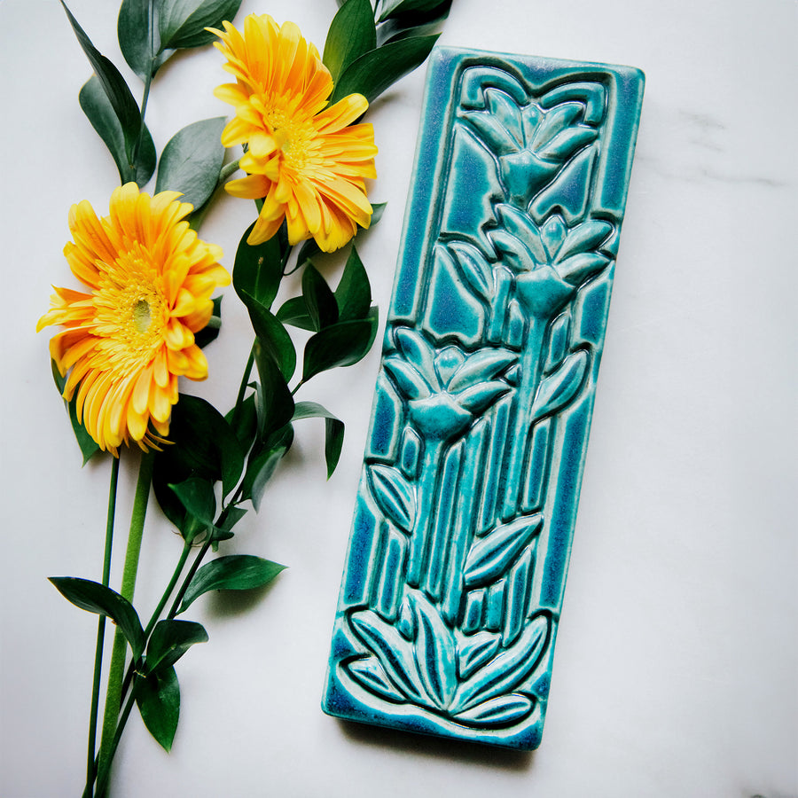 This large Floral Tile features three tall art deco-esque flowers on long straight stems with pointed leaves.