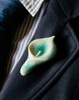 Ceramic Calla Lily Pin in pale glossy blue glaze used as a boutonniere on a suit lapel.