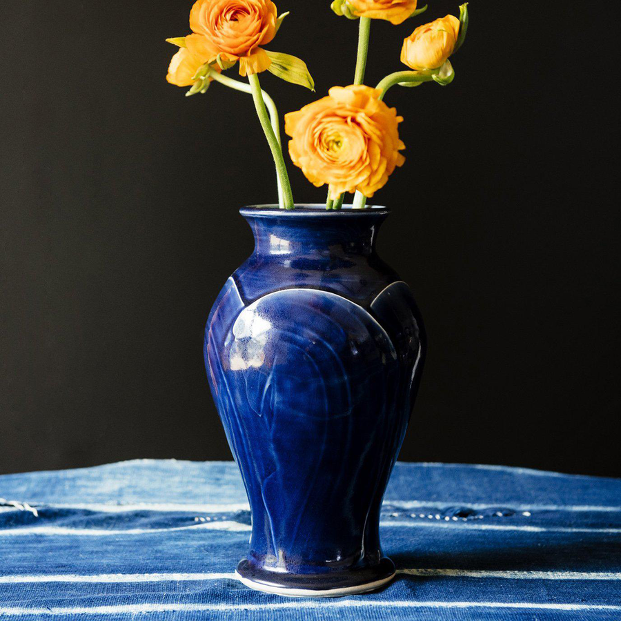 The Large Classic Vase starts with a small diameter at its base that gradually gets larger until it contracts again near the top with a slightly wider lip. The sides of the vase have been swiped with slip, this gives the appearance of abstract petals overlapping on the widest part of the vase. This Classic Vase features the glossy deep dark blue Midnight glaze.