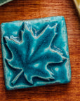The Pewabic blue glazed maple leaf tile is featured. This tile is a matte turquoise blue.