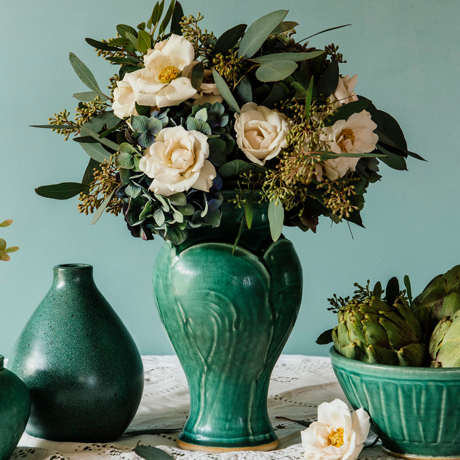 The Medium Classic Vase starts with a small diameter at its base that gradually gets larger until it contracts again near the top with a slightly wider lip. The sides of the vase have been swiped with slip, this gives the appearance of abstract petals overlapping on the widest part of the vase. This Classic Vase features the matte blueish-green Pewabic Green glaze.