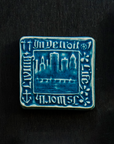 The Old Detroit Tile features an image of the Detroit skyline circa 1906 with the Belle Isle Bridge and the waters of the Detroit river in the foreground. A thick border around the design says "In Detroit Life is Worth Living" with a small symbol of four Detroit industries in each corner.