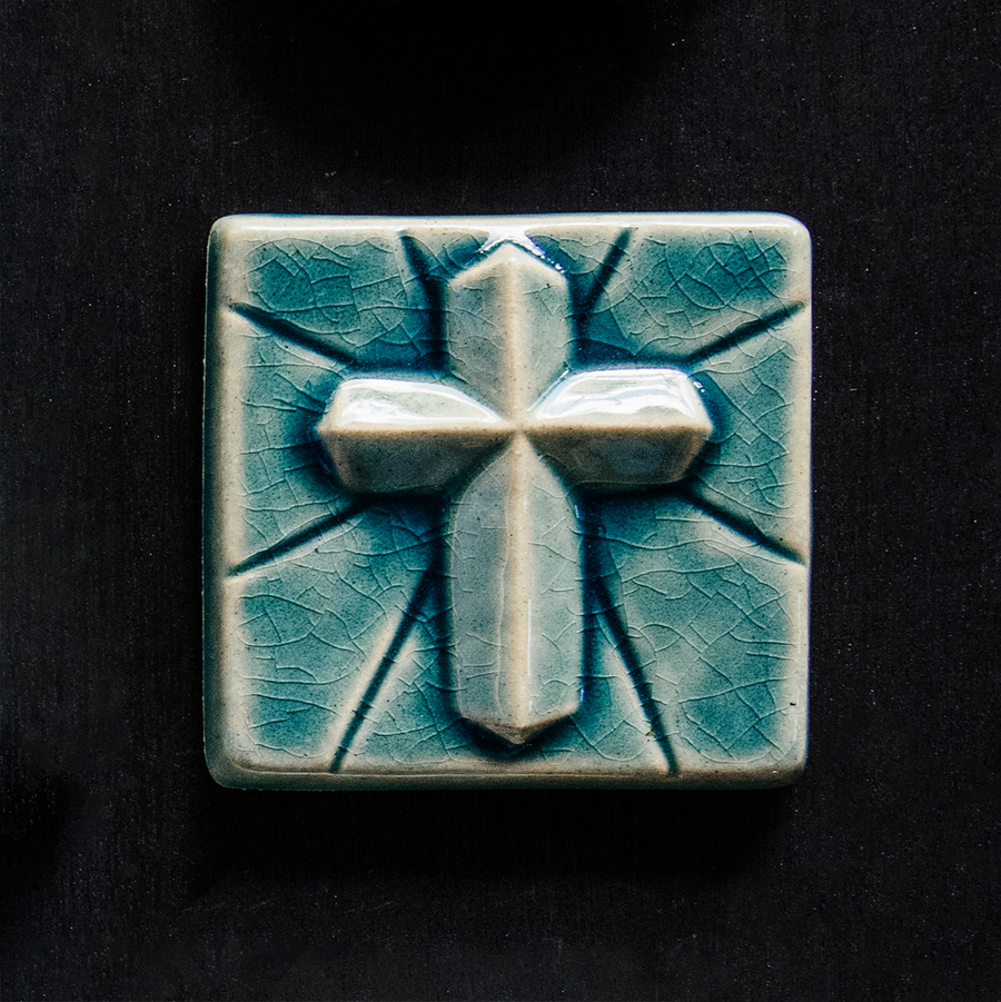The Mario's Cross Tile features a geometric 3d cross with simple lines emanating from it. This tile features the medium blue Glacier Gloss glaze.