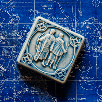 The Gemini tile in Celestite glaze sits on a vintage blue and white map of the celestial sky.