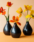 A trio of Teardrop Vases with bright, red and yellow tulips on a bright orange backdrop