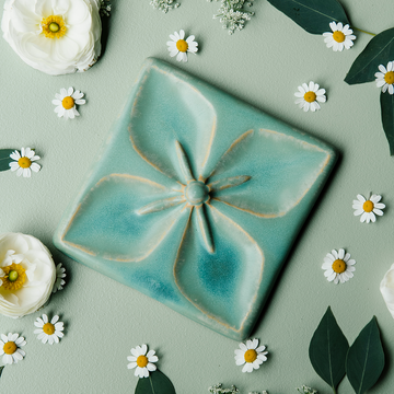 The Flower Geo Tile features a four-petaled flower. Each petal takes up a quarter of the tile, making a perfectly geometric shape. The inner part of the flower is round with four cattail shaped stamen exploding from the center that point out to the corners of the tile.