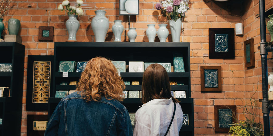 Two young women peruse a selection of colorful tiles displayed in the historic Pewabic gallery store.