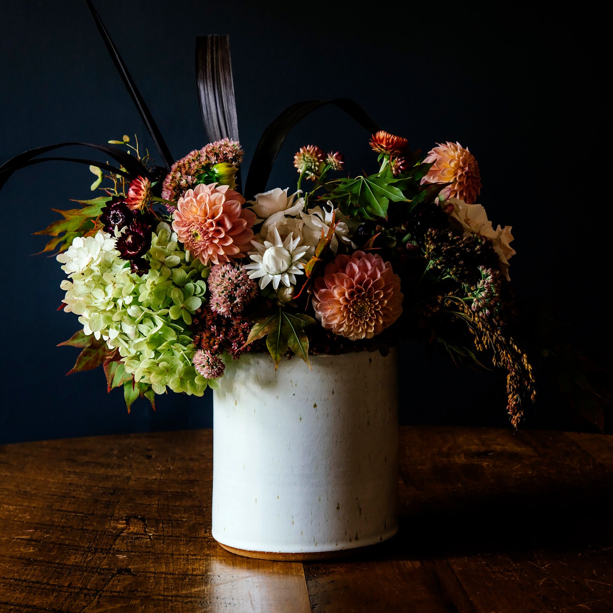 The crock is a cylindrical vessel with straight sides that has a wide opening and is as wide as it is tall. This Pewabic crock features the glossy, steel blue Ultramarine glaze.