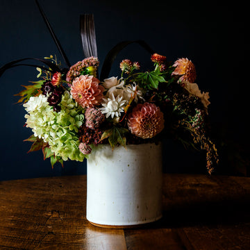 The crock is a cylindrical vessel with straight sides that has a wide opening and is as wide as it is tall. This Pewabic crock features the glossy, steel blue Ultramarine glaze.