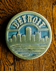 The Detroit Trivet features the Detroit skyline with the Renaissance Center in the middle. The word "Detroit" is carved along the top of the circular tile in an Olde English font similar to the one used for the Detroit Tigers' logo. 