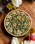 The round Ivy Trivet features a long branch of leafy ivy that curves into a spiral that ends in the center of the trivet. 