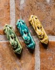 This ceramic Mezuzah features an acorn and oak leaf with the word "Peace" written in Hebrew below them. This piece is thick with an opening on the back to hold your written prayer. There are two holes at the top and bottom to make it easy to attach to your doorframe.