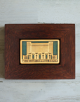 The Michigan Central Depot Tile features the image of the large many-windowed building with the words "Michigan Central Depot" across the bottom of the tile. The two toned nature of the tile means that the design and words have been scraped of their glaze giving them a creamy off-white look while the background of the image is in the crystalline, shimmering deep green Viridian glaze. The oak wood frame is a deep reddish brown color.