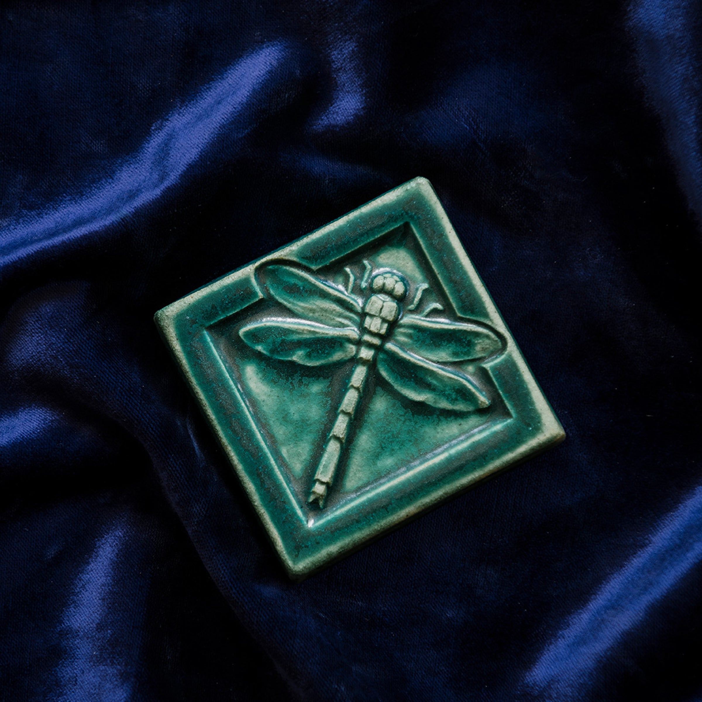 This Dragonfly Tile features the matte blueish-green Pewabic Green glaze on a rich blue velvet backdrop. 