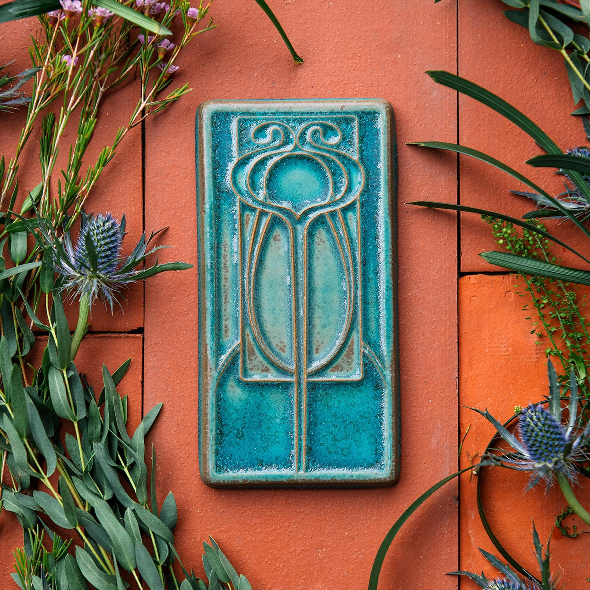 This vertical rectangle tile has an abstract low relief design. Interconnecting hard and curved lines come together to create a craftsman style motif.