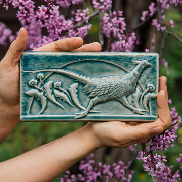 This hand-sculpted tile features a pheasant running through a field of dandelions. It is featured in a glossy blue Glacier glaze. 