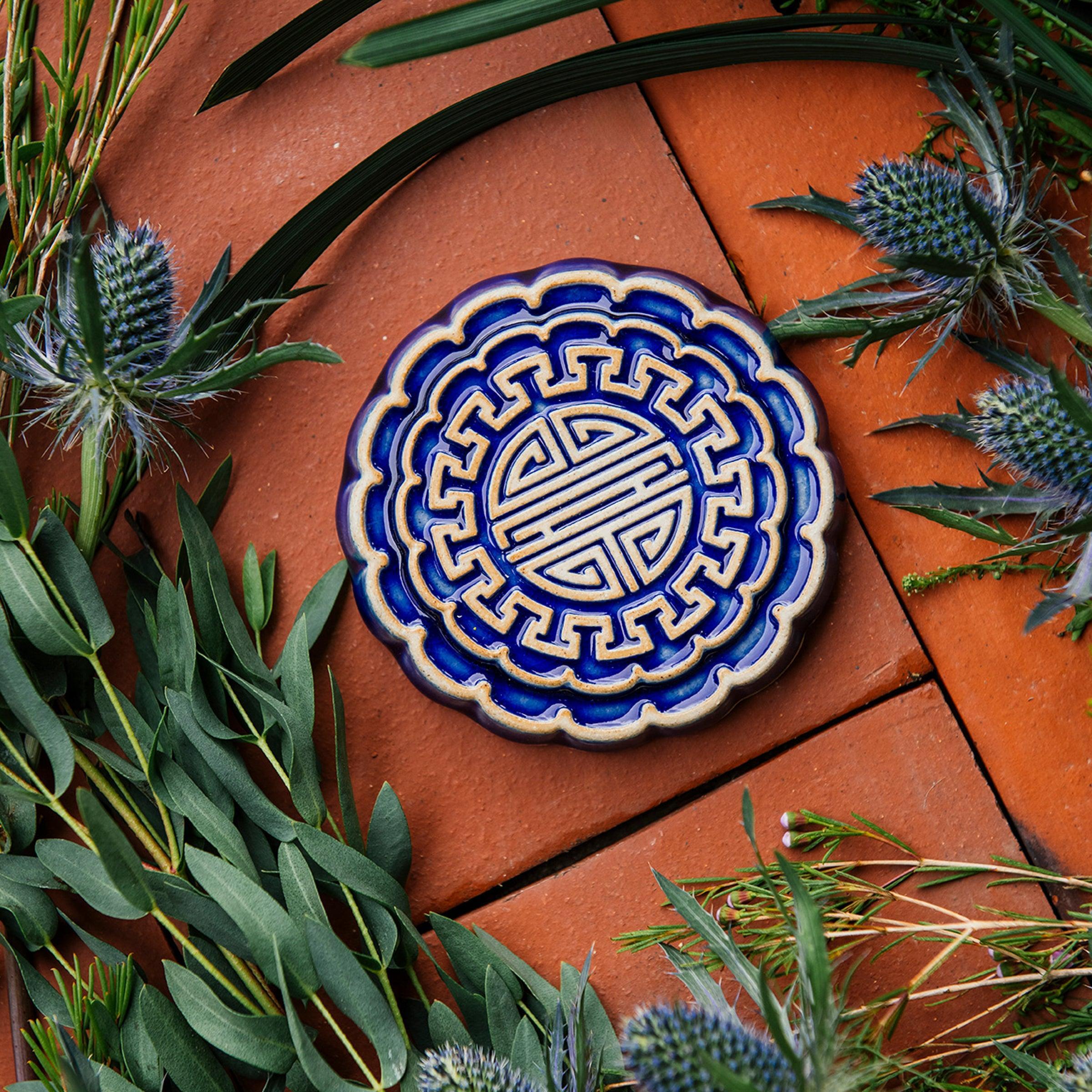 A Mooncake Paperweight in two-tone Lapis/Scrape surrounded by thistle and wax flowers.