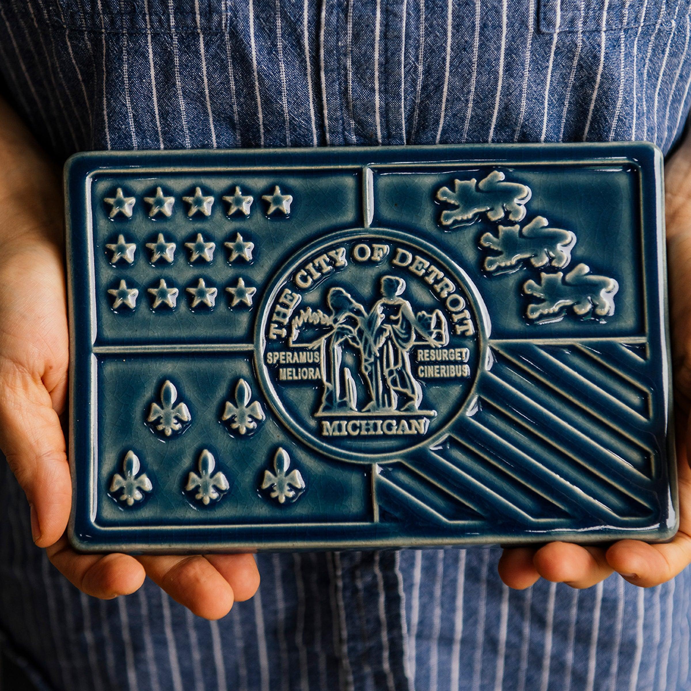 Hands hold the Detroit Flag Tile.