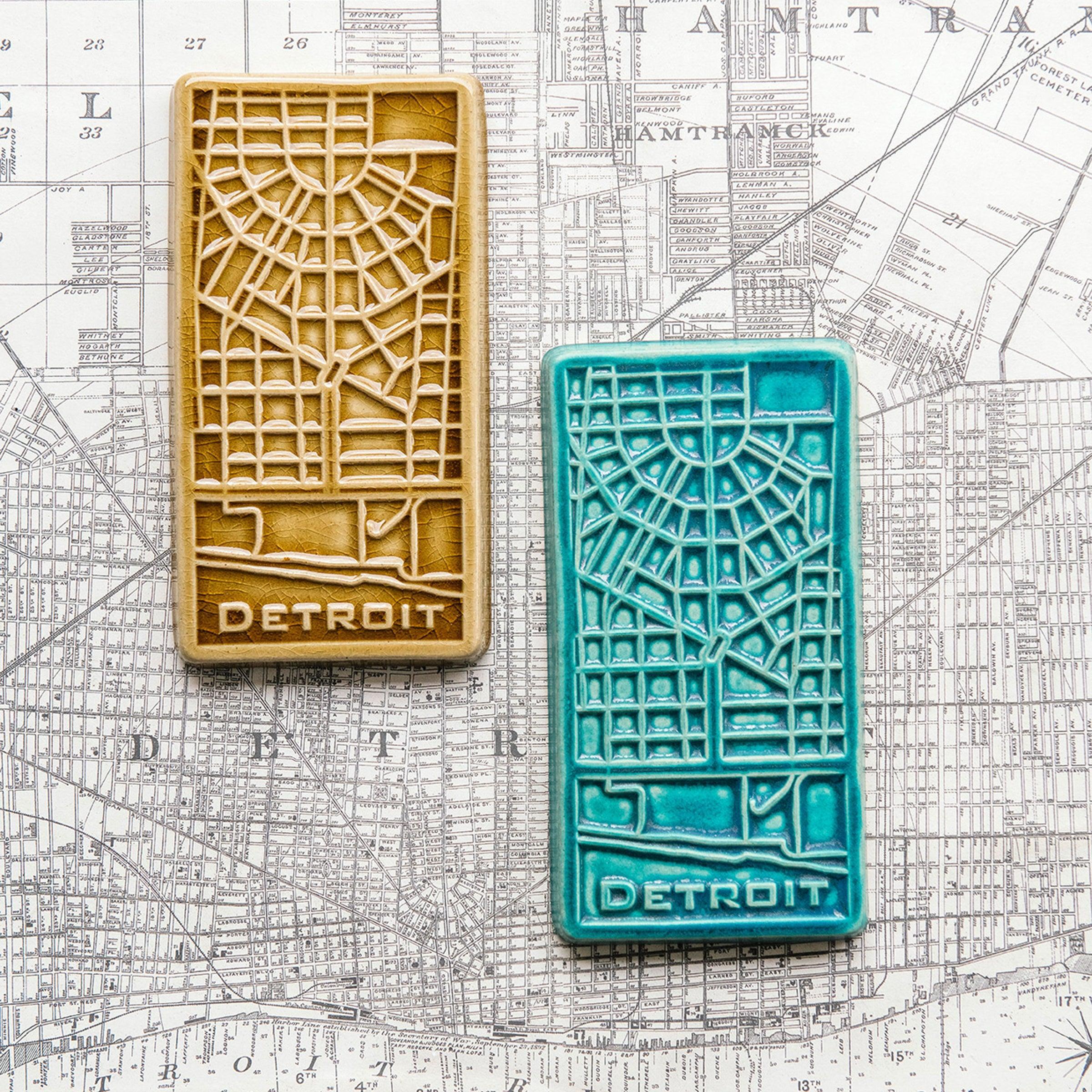 This rectangular Detroit Map Tile has a line drawing of the areal street view of downtown Detroit. The word "Detroit" is written at the bottom of the design.