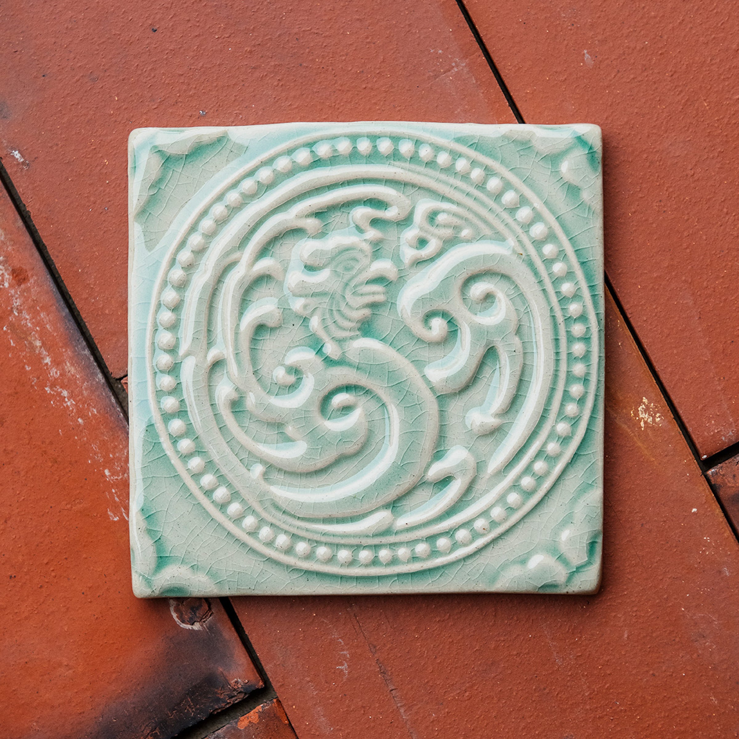 This celadon Phoenix rests on terracotta roof tiles.