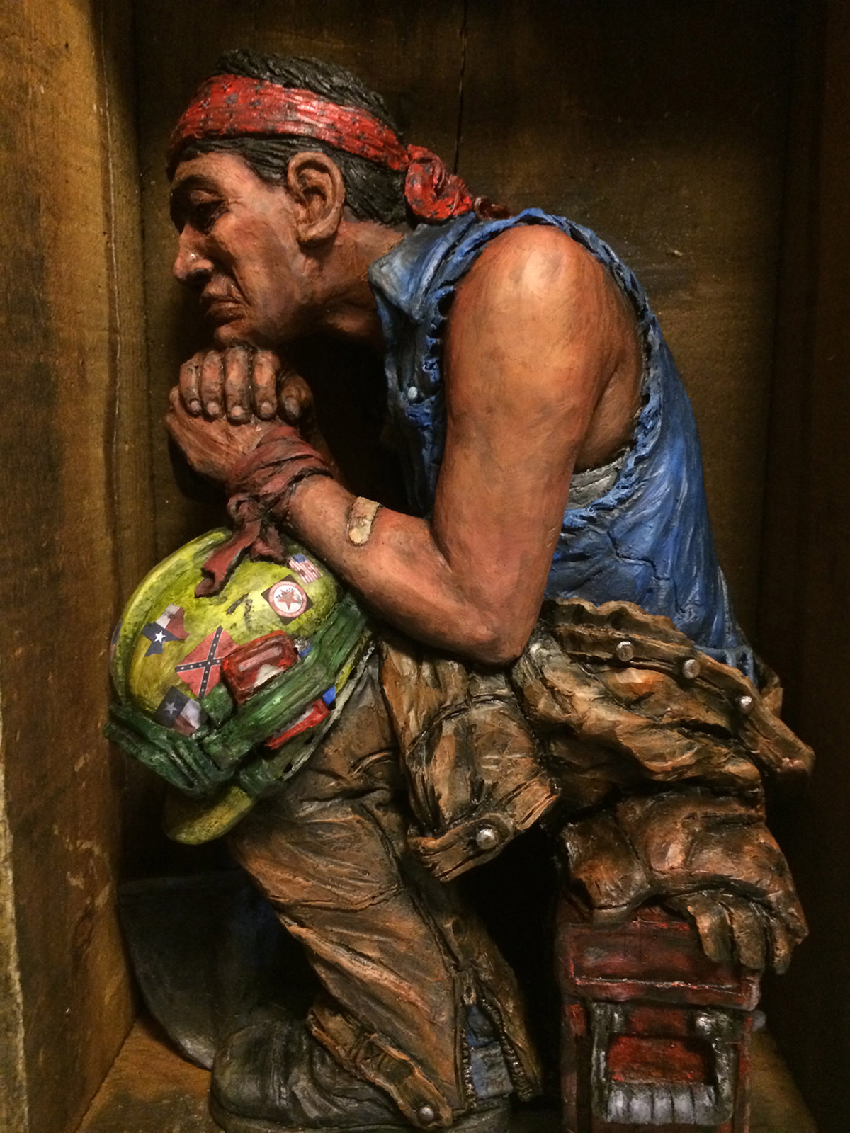 The man is sitting on a tool box, his eyes closed and a slight frown on his face.