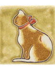Palatte B is a orangy-brown and white spotted cat with a red collared bow resting on a yellow cream background.