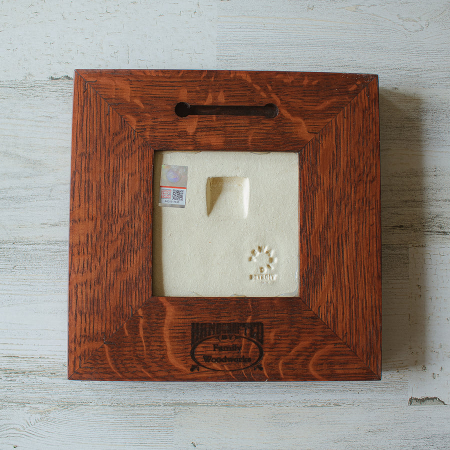 The back of the framed piece shows the open-back structure of the frame. This exposes the Pewabic Stamp one the back of the tile as well as the official sports licensing sticker. There is a burned on stamp of the woodworker who created the frame- it says "Handcrafted Family Woodworks".