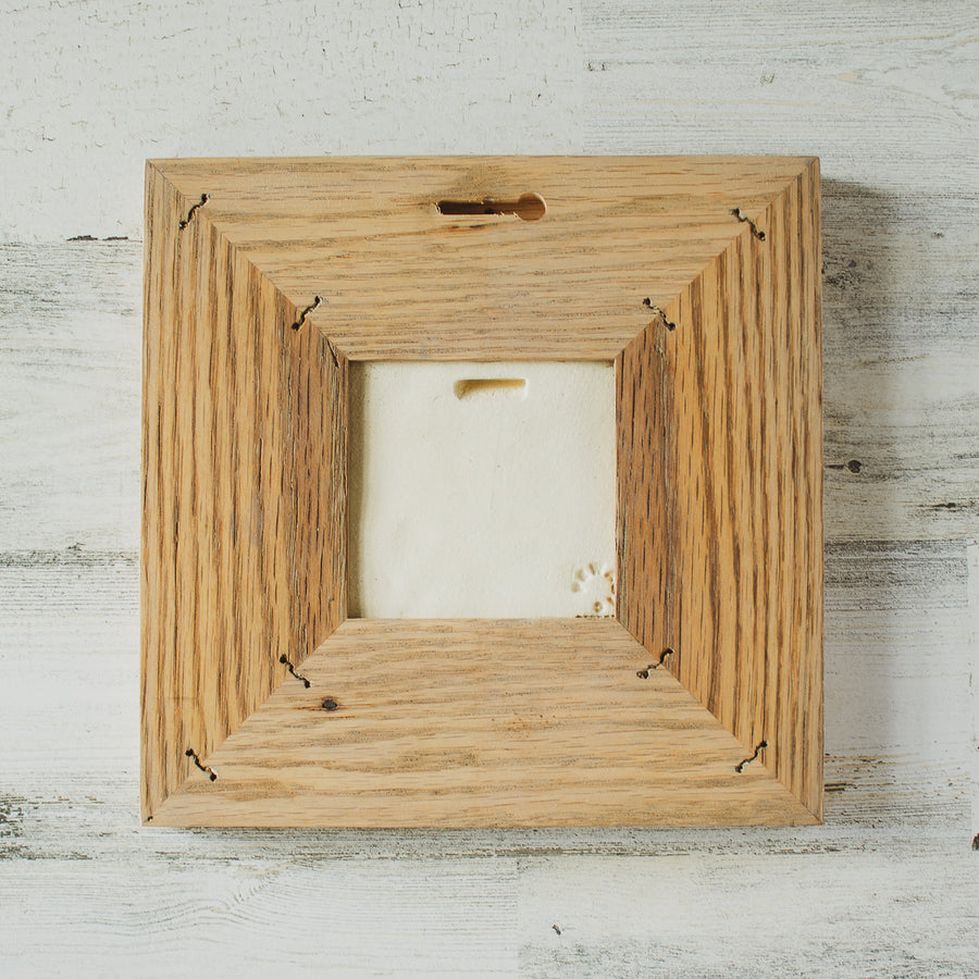 The back of the framed piece shows the open-back structure of the frame. This exposes the Pewabic Stamp on the back of the tile.