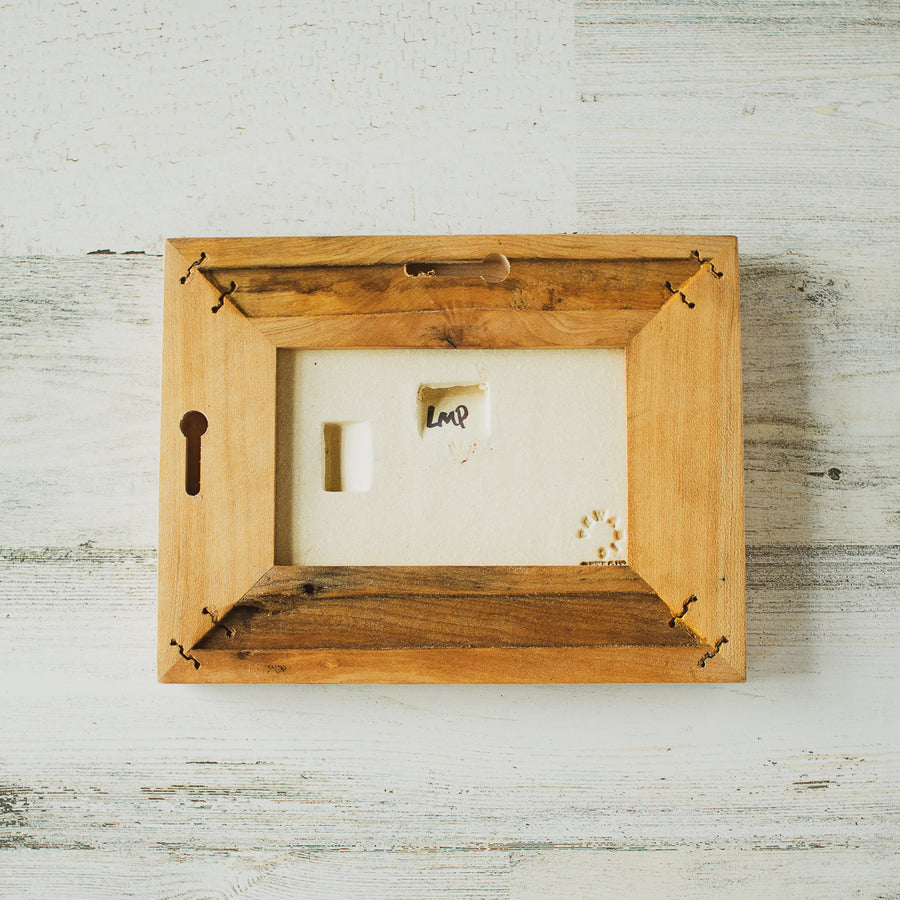 The back of the framed piece shows the open-back structure of the frame. This exposes the Pewabic Stamp on the back of the tile as well as the hand-written initials of the glazer who hand-painted the piece- in this case it says LMP. You can hang this piece horizontally or vertically so there are nail holes on the top and side of the frame.