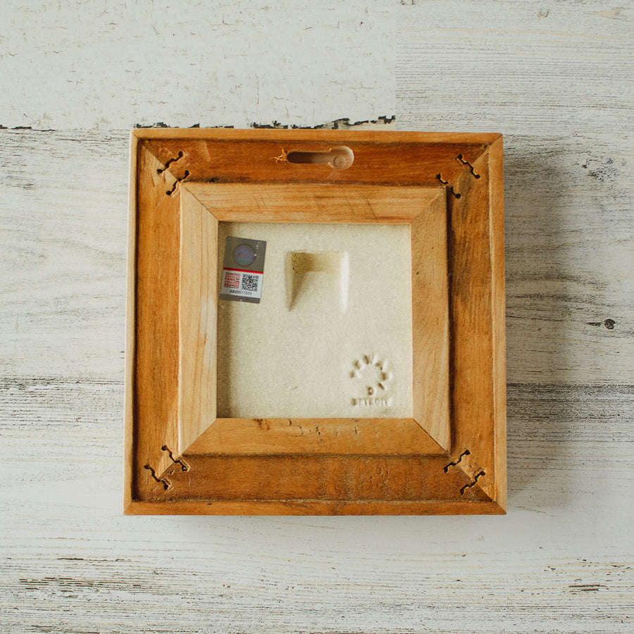 The back of the framed piece shows the open-back structure of the frame. This exposes the Pewabic Stamp on the back of the tile as well as the holographic licensing sticker. 