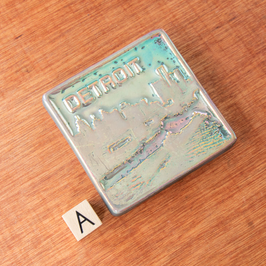 A Detroit tile with a metallic finish sits next to the letter A to delineate which option is represented.