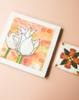 These Kathleen Casper Tiles are hand-painted in shades of orange, red and green. The smaller tile (Style A) has the design of an abstract flower with petals that make a perfect x. The background of the square 4x4 tile is white.