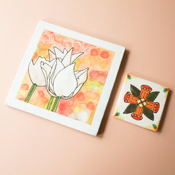 These Kathleen Casper Tiles are hand-painted in shades of orange, red and green. The smaller tile (Style A) has the design of an abstract flower with petals that make a perfect x. The background of the square 4x4 tile is white.